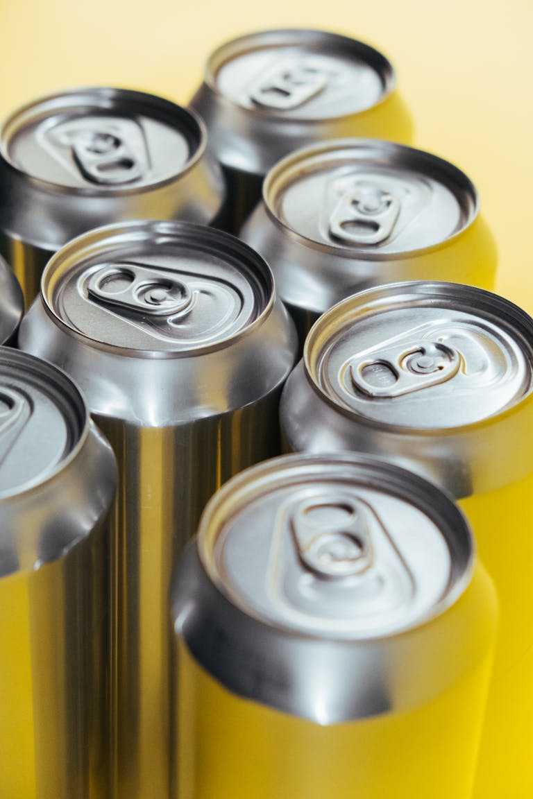 Close-up product shot of aluminum beverage cans on a vibrant yellow background.